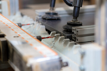 Drilling holes in a board with an industrial drill in a production furniture workshop