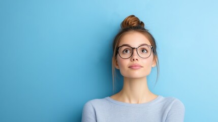 Fototapeta premium Young Woman with Glasses Posing Thoughtfully Against Blue Wall Background