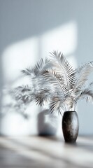 Dried palm fronds arranged in a dark vase with light and shadow playing on a white wall and wooden floor, creating a minimalist, serene atmosphere