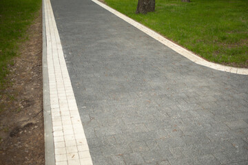 Obraz premium A path in the park. Tile driveway. Empty area.
