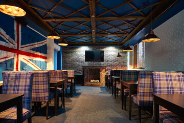 A cozy and stylish restaurant or English-style pub interior with checkered chairs, brick walls, and the Union Jack flag of Great Britain. United Kingdom decor. UK
