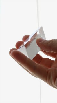 Rectangular crystallized prism for light bending.
Close-up of quadrangular prism.
Glass prism in hands macro video