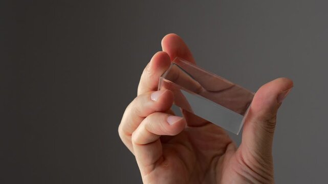 Rectangular crystallized prism for light bending.
Close-up of quadrangular prism.
Glass prism in hands macro video