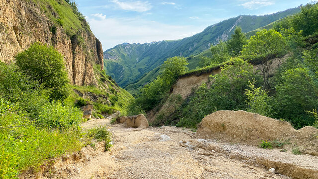 A dirt mountain road running along the bottom of an unusual canyon in Azerbaijan. Trekking from Laza village to Kuzun village. A scenic one-day route - Powered by Adobe