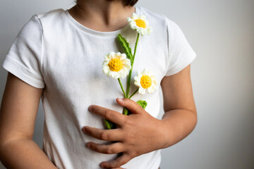 Young child holding handmade crochet flowers in white shirt