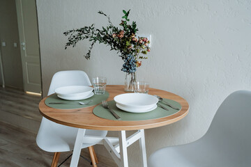 Stylish Dining Arrangement A modern round table adorned with a fresh floral centerpiece, creating an inviting and comfortable atmosphere, perfect for gatherings and enjoyable meals with loved ones