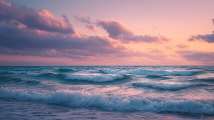 Obraz premium Gentle waves roll onto the shore as the sky is painted with pastel hues of pink and purple during sunset. The tranquil scene captures the beauty of nature at dusk.