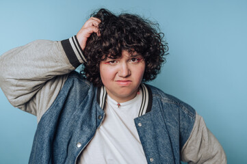 Obraz premium portrait of young woman scratches their head with a confused look, blending humor and a casual aesthetic in a lighthearted moment on blue background