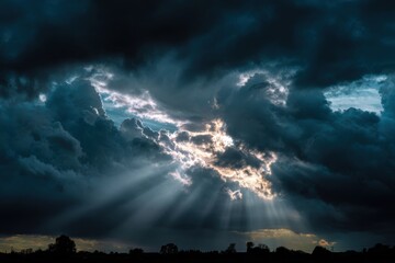 Dramatic sky with sunbeams piercing dark clouds.  Vast expanse of ominous storm clouds, with a light breaking through