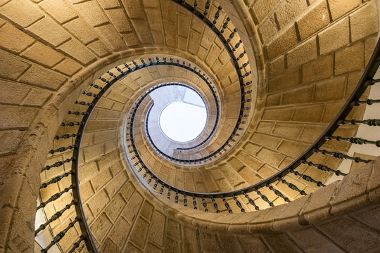 Looking up at a spiral staircase inside a dark building interior