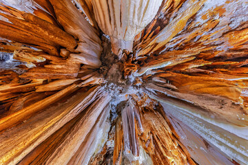 Obraz premium Aerial view of mineral stalactites in an illuminated underground cave