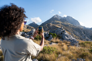 Adventurous woman photographs Puig Major in the Sierra de Tramuntana, Majorca. Concept of tourism,...