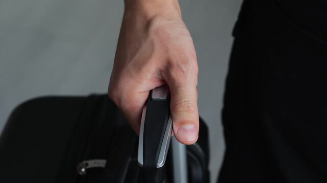 A man holds a metal handle on a suitcase while standing at an airport.
A large suitcase for carrying luggage.
Luggage in a gray suitcase.
A man with a suitcase at a train station