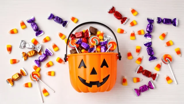 Vibrant Flat Lay of Pumpkin Candy Bucket with Scattered Sweets