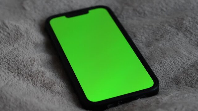 Smartphone with green display lies on the surface.
Office worker's workplace.
Green screen to replace background