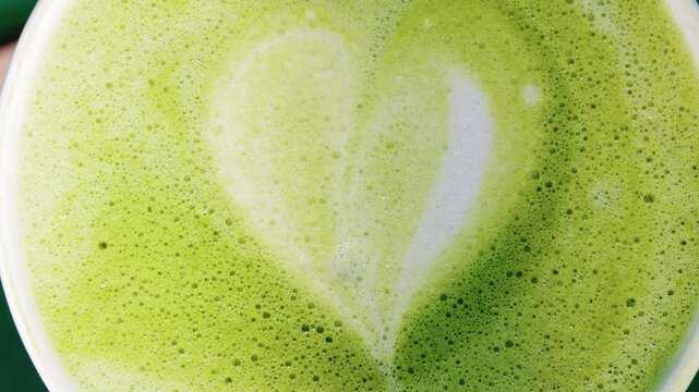 Close up of a frothy matcha latte with heart-shaped latte art