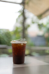Close up of take away plastic cup of iced black coffee or iced Americano at outdoor table