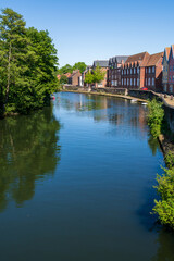 The Norwich riverside scene features historic, colourful houses reflected in the peaceful waters of the river. English heritage buildings line the waterway in the Norfolk city centre
