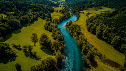 Aerial view of a vibrant turquoise river winding through lush green forests and meadows