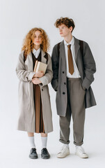 Young Students in Classic Uniform and Coats Standing with Books on White Background
