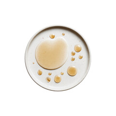 Overhead View of Light Brown Liquid Spilled on Speckled White Plate