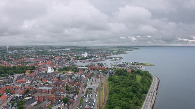 Daytime aerial panorama of Thisted, Denmark &mdash; Skyline view of historic houses, white church, marina, and dramatic sky over the Limfjord waterfront in North Jutland