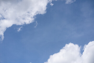 A wideangle view of a clear blue sky with a fluffy white cloud formation stretching across the bottom and a smaller cloud in the upper corner.The image is an ideal background symbolizing calmnes