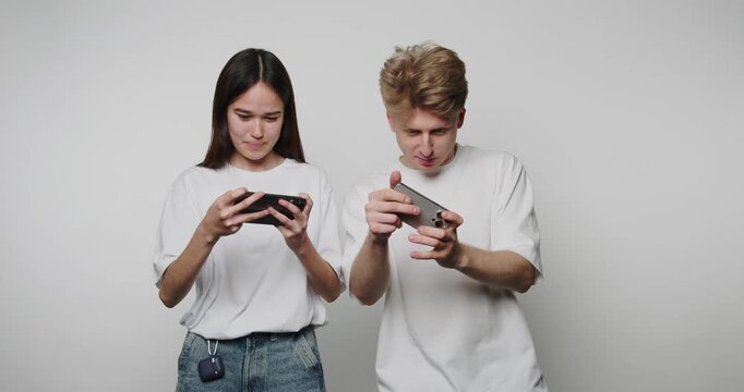 footage of young man triumphantly celebrates a win over his girlfriend while playing smartphone games on white background