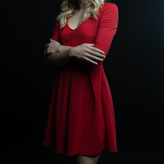 Fototapeta premium Elegant blonde woman posing in red dress on black background