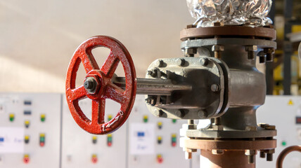 Red valve on industrial pipeline in boiler room