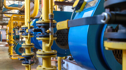 Industrial boiler room with yellow gas pipes and blue boilers