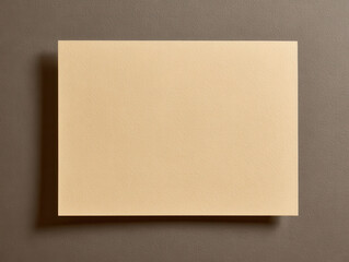 Blank beige paper lies on textured brown surface, casting subtle shadow. simplicity and neutral tones create calm and minimalist aesthetic, ideal for design or stationery concepts