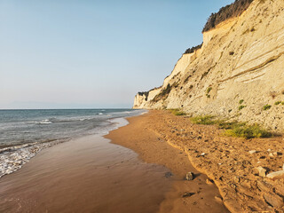 Sandy beach at the base of pale cliffs in Agios Stefanos, Corfu, Greece, on a sunny summer day