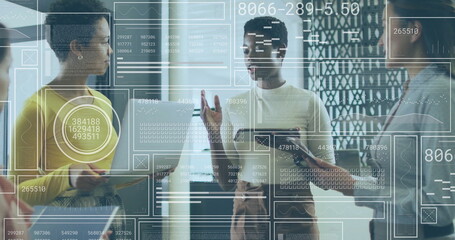 Presenting Black office professional pointing at digital charts in conference area, with tablet