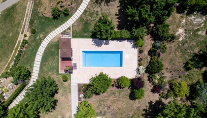 Aerial view of a rectangular pool, patio, and surrounding landscape