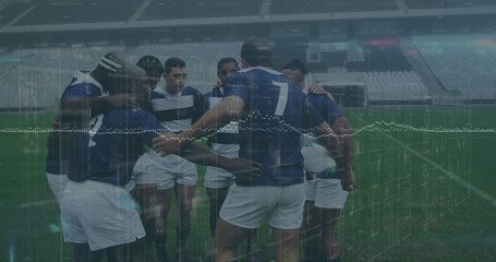 Huddling rugby players in jerseys discussing tactics on stadium pitch, with rugby ball and lights