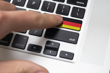 Online International Business concept: Computer key with the Germany flag on it. Male hand pressing computer key with Germany flag