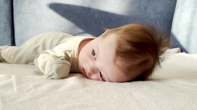 A small newborn baby lies on its stomach and tries to raise its head. Concept of healthy development of baby 0-6 months, baby care.