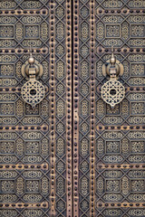 Close-up of a traditional Moroccan door at Hassan Tower in Rabat, Morocco. The ornate brass knockers and intricate geometric patterns showcase Islamic Moorish craftsmanship and cultural heritage