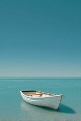 Naklejka premium A white rowboat drifts peacefully on the calm sea, surrounded by clear blue waters and an unblemished sky. Nature's serenity is highlighted during this tranquil moment