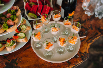 Food photography. Buffet, catering at a festive banquet of fresh fruits, appetizers, sandwiches, cocktails on a wooden table outdoors.
