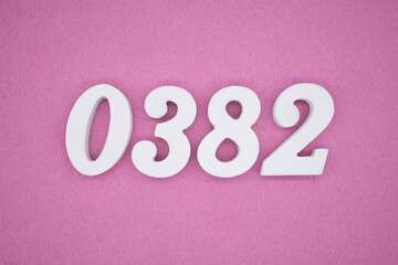 The numbers are made of white painted wood, placed on a pink paper background.