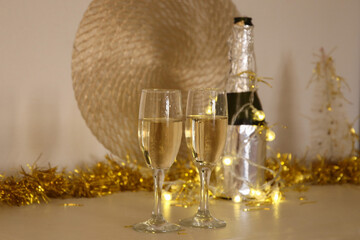 Two Champagne flutes on table. Christmas tree background. Festive Card for New Year.