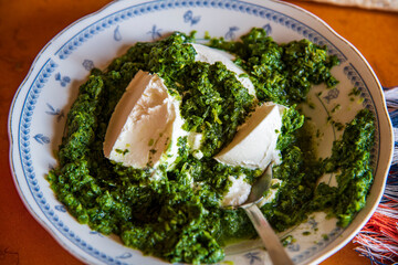 Preparation of homemade spinach pie with filo pastry sheets, showing fresh spinach filling being layered and arranged before baking. Step-by-step cooking process highlighting ingredients, textures...