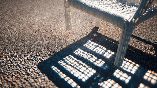 Shadow of a chair on a textured ground with sunlight creating patterns.
