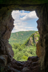 View through the loophole of a medieval fortress. Excellent overview of the nearby hills and forests. Bright blue sky with clouds. Khuluti fortress.