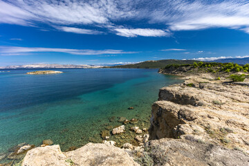 Azure water in the Adriatic Sea, rocky coast of the island of Rab, cloudy, threatening sky,