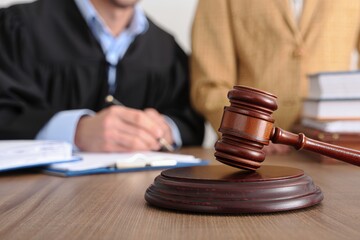 Judge's Gavel on Table with Legal Documents and Professionals in Background