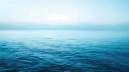 Calm, blue ocean water rippling under a bright sky, receding into soft, blurred horizon
