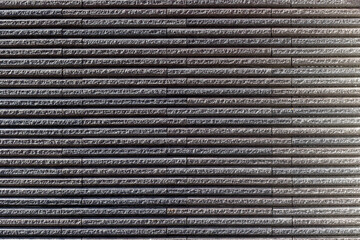 Textured gray stone wall with horizontal layers and shadows